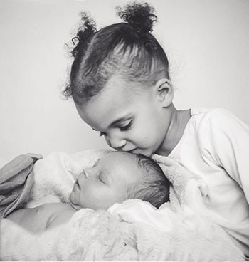 Photo of a young girl kissing a baby